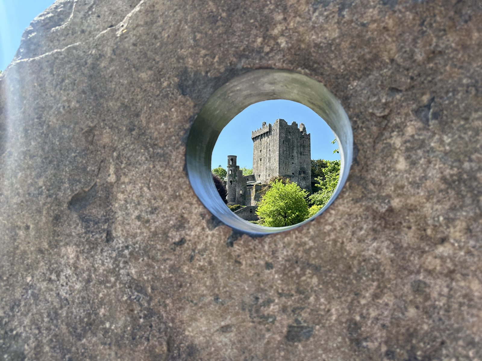 The castle tower framed inside the round hole cut through the standing stone