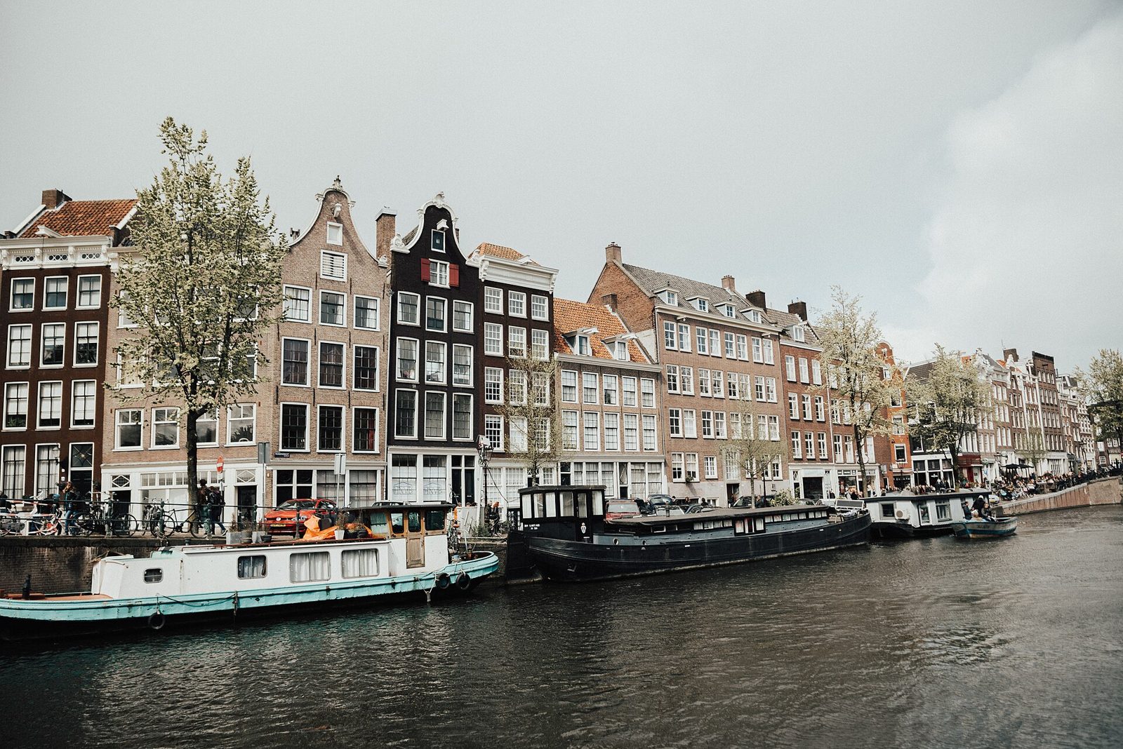 A row of narrow Amsterdam canal houses with stepped gables, reflected in the water below