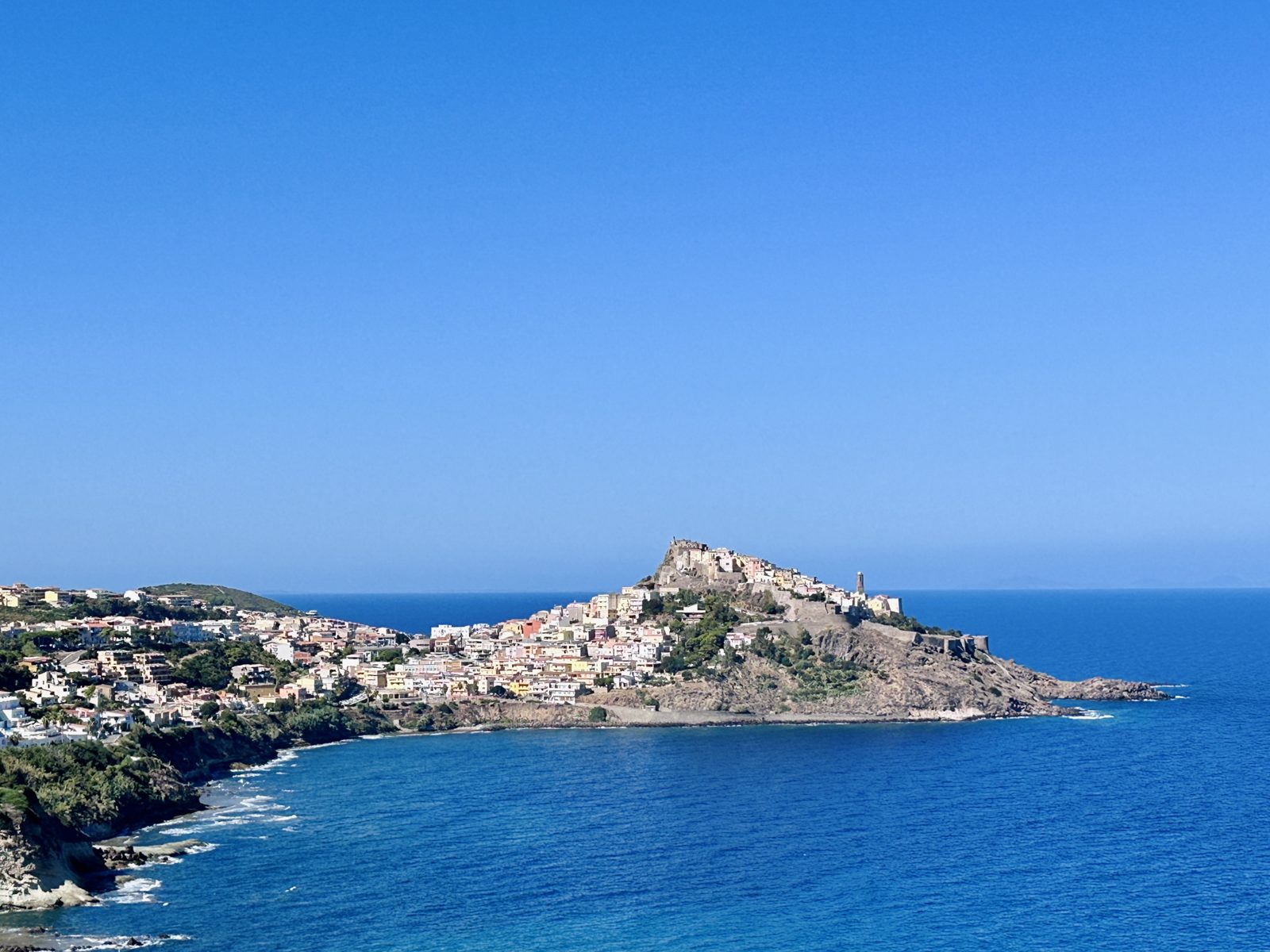The walled town of Castelsardo stacked up its headland above deep blue sea, with the castle at the top and pale houses running down to the water