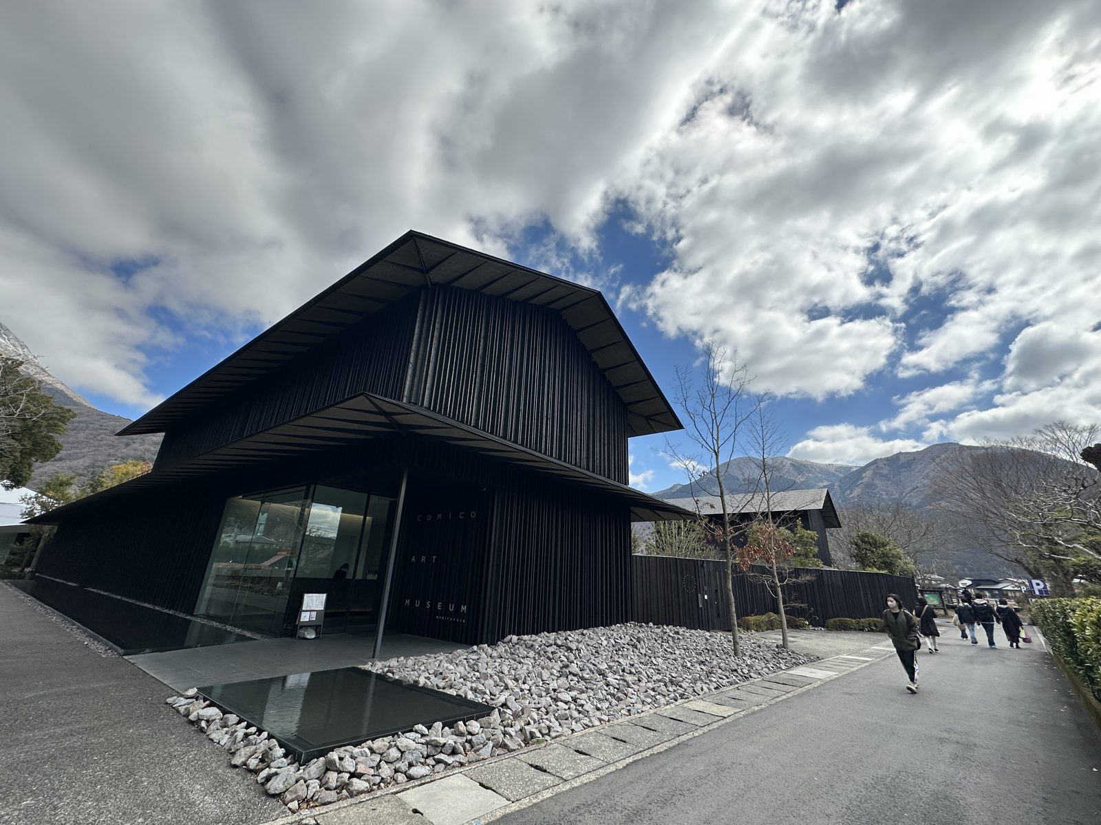 The entrance to the Comico Art Museum, black timber walls beside a shallow reflecting pool and a bed of pale stones