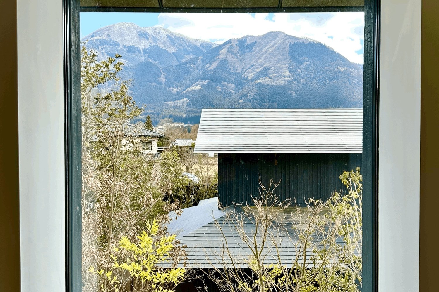 The view from a ryokan room window, snow topped mountains beyond a dark timber roof