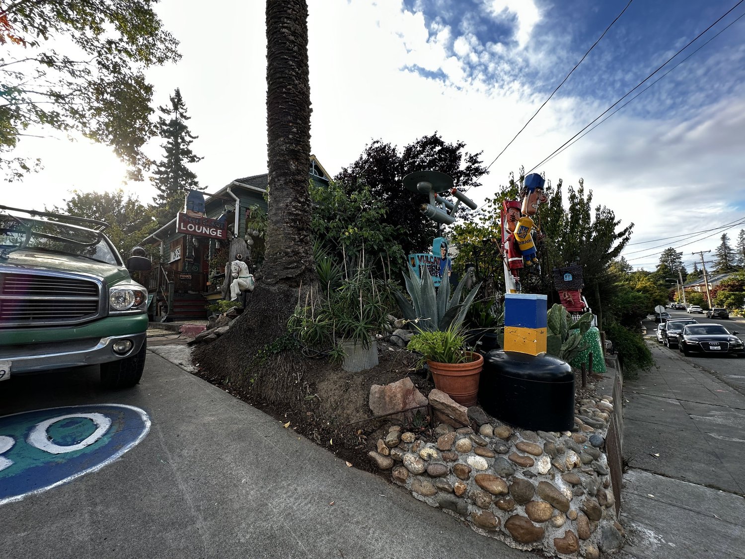 A view down Florence Avenue past a palm tree, with a starship sculpture and painted figures lining the sidewalk