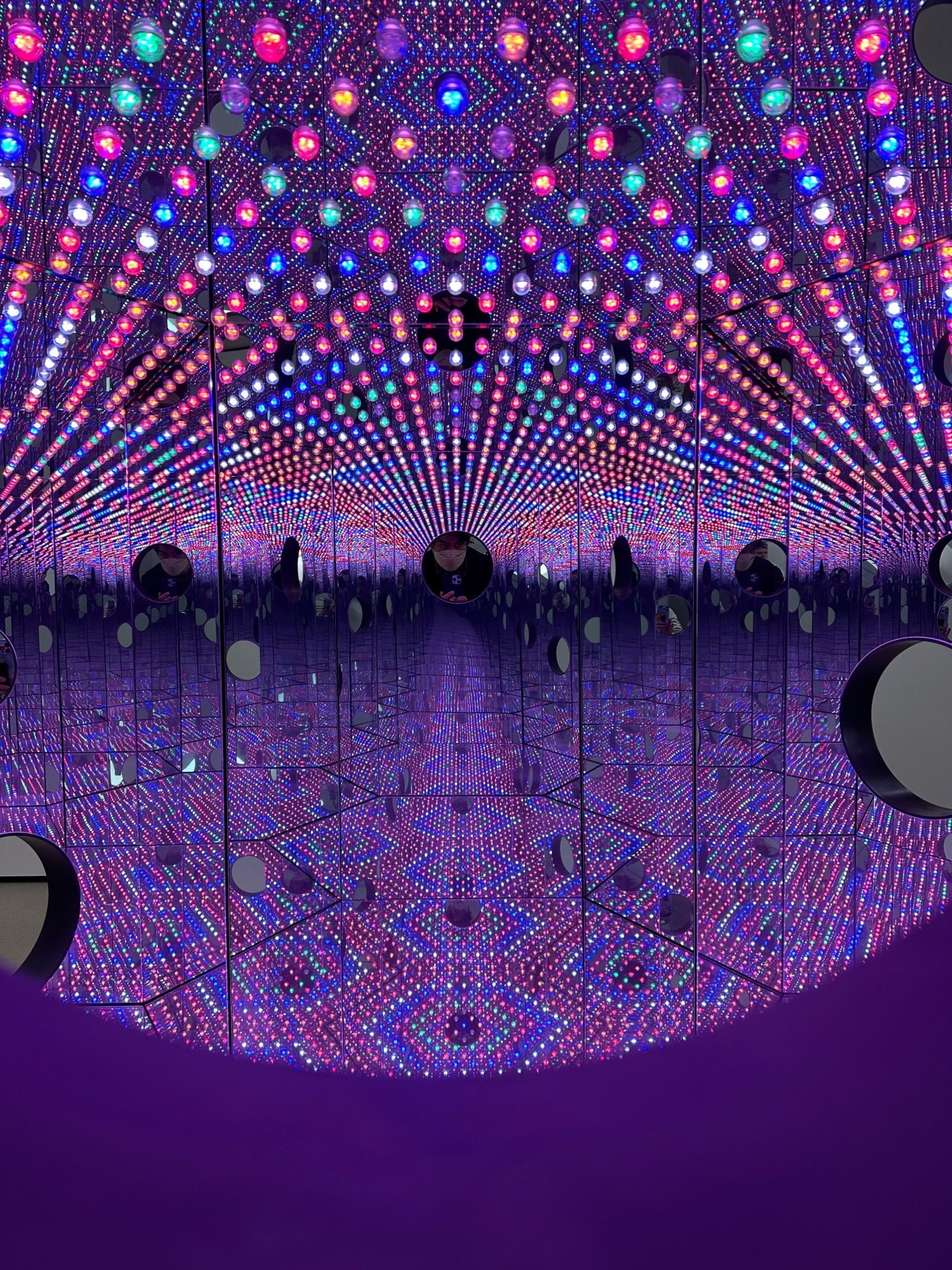 Inside a Yayoi Kusama infinity mirror room, endless pink and blue lights reflecting in every direction
