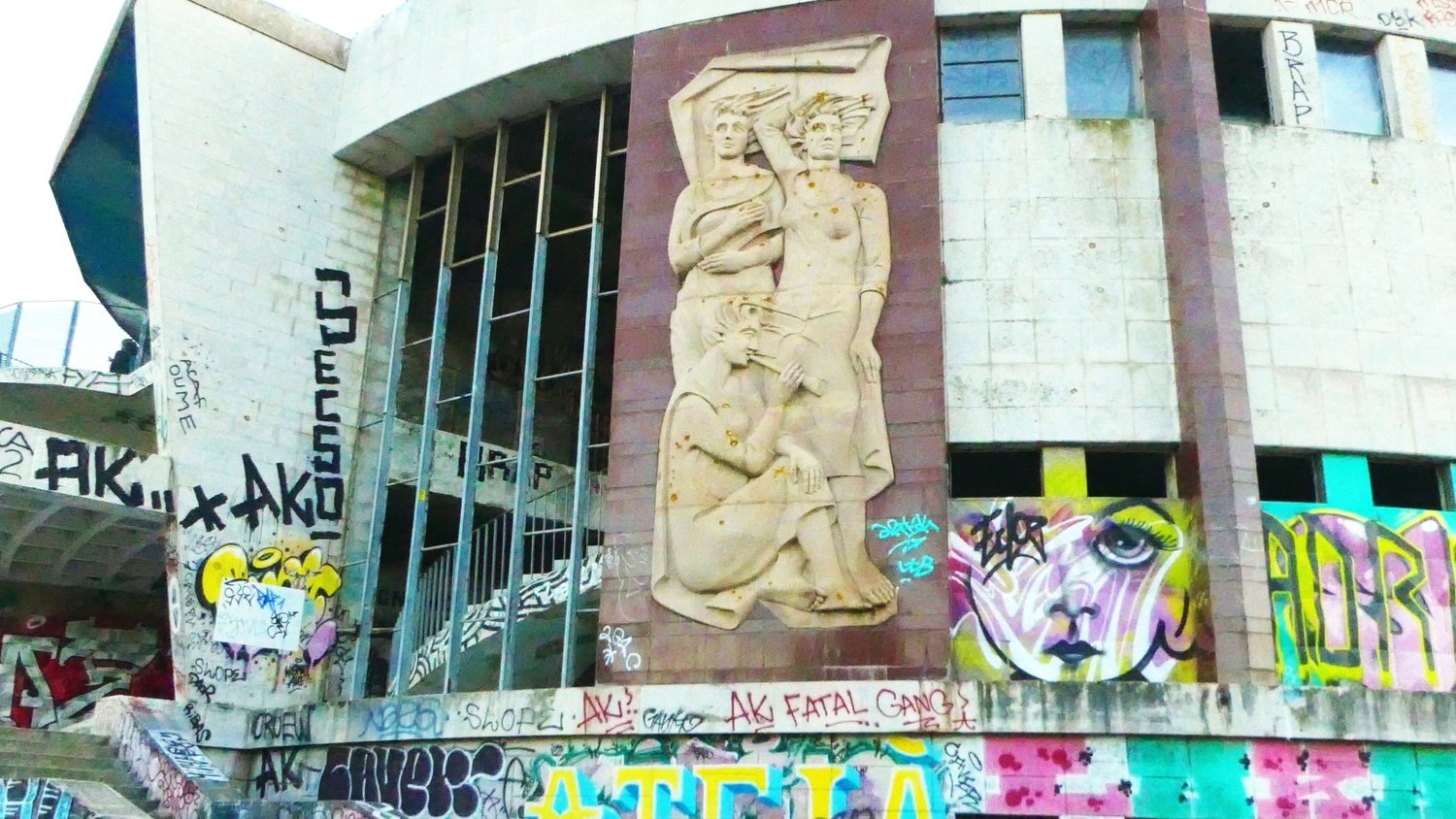 A carved stone relief of three figures on the graffiti covered concrete facade of the abandoned Panoramico de Monsanto