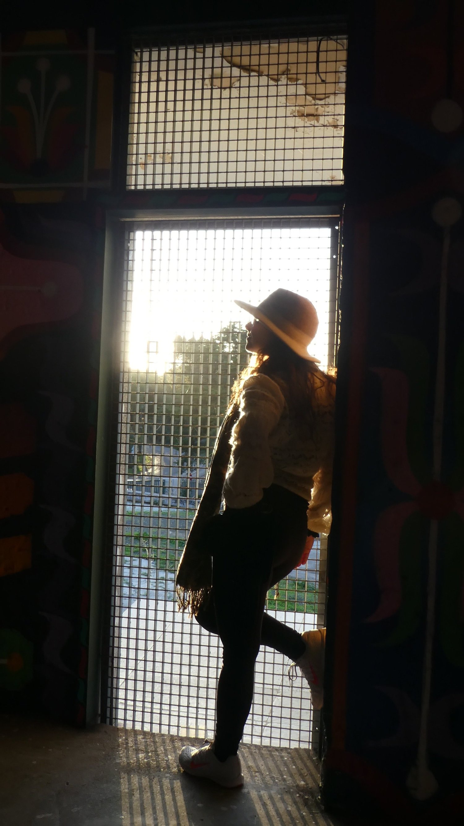 A visitor silhouetted in a grated doorway of the abandoned viewpoint, backlit by low sun