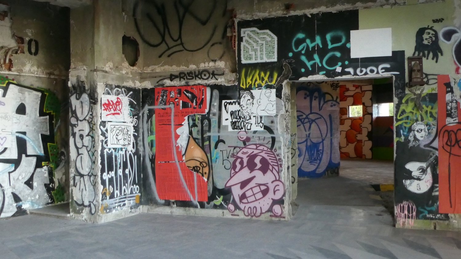 Interior walls of the ruin covered in spray paint, pasted posters and stencilled portraits