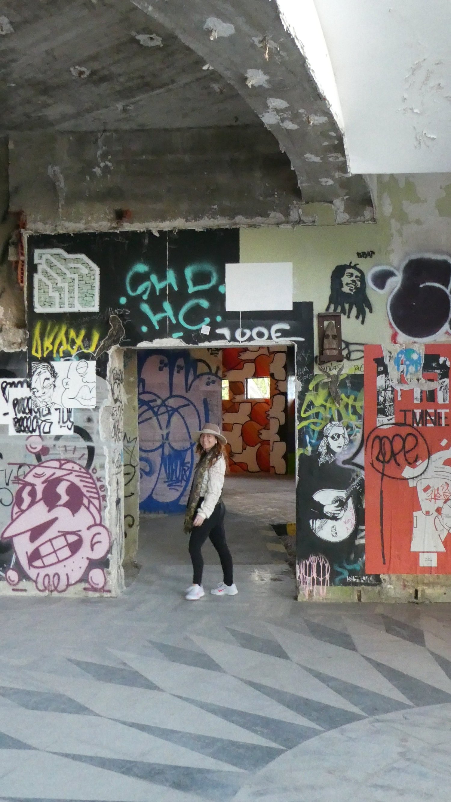 A visitor standing in a graffiti framed doorway on the patterned stone floor of the ruin