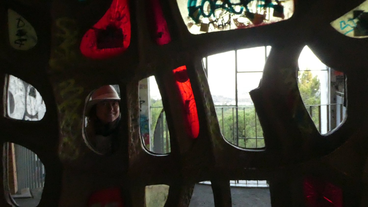 Looking through the openings of the concrete screen wall, a visitor's face framed in one gap and Lisbon beyond